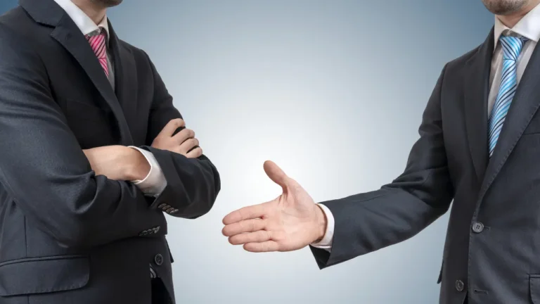 Homme d'affaires refusant de serrer la main d'un autre, symbolisant un refus de prêt immobilier par la banque