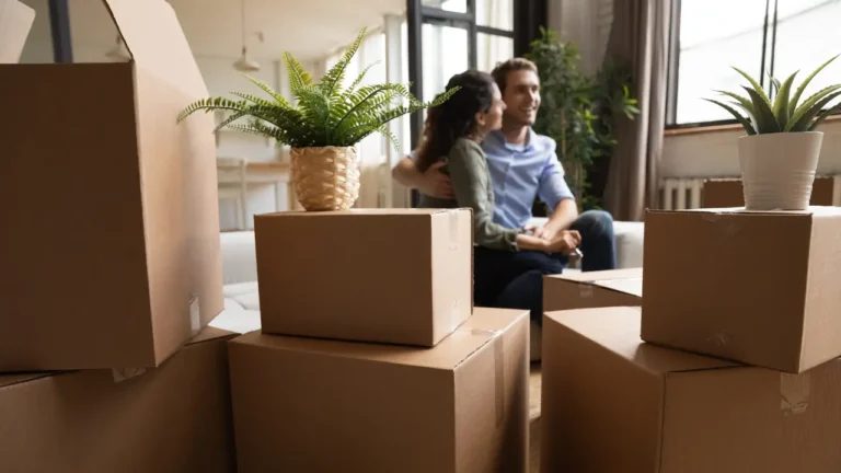 Couple de primo-accédants dans leur nouveau logement entouré de cartons de déménagement, illustrant les aides et prêts disponibles pour un premier achat immobilier en 2026.