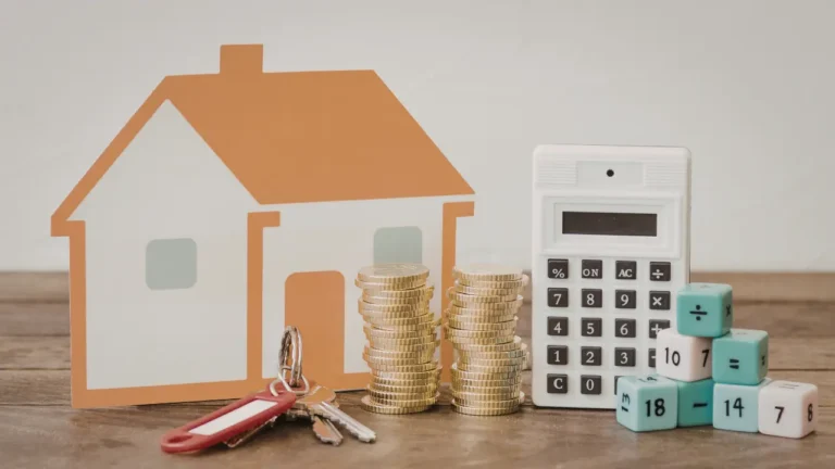Maison symbolique, piles de pièces et calculatrice illustrant le prêt d’accession sociale, les conditions de financement et le calcul des mensualités pour devenir propriétaire en 2026.