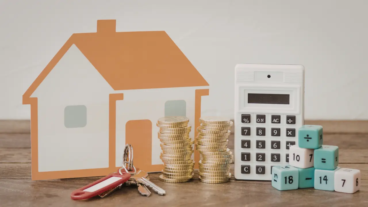 Maison symbolique, piles de pièces et calculatrice illustrant le prêt d’accession sociale, les conditions de financement et le calcul des mensualités pour devenir propriétaire en 2026.